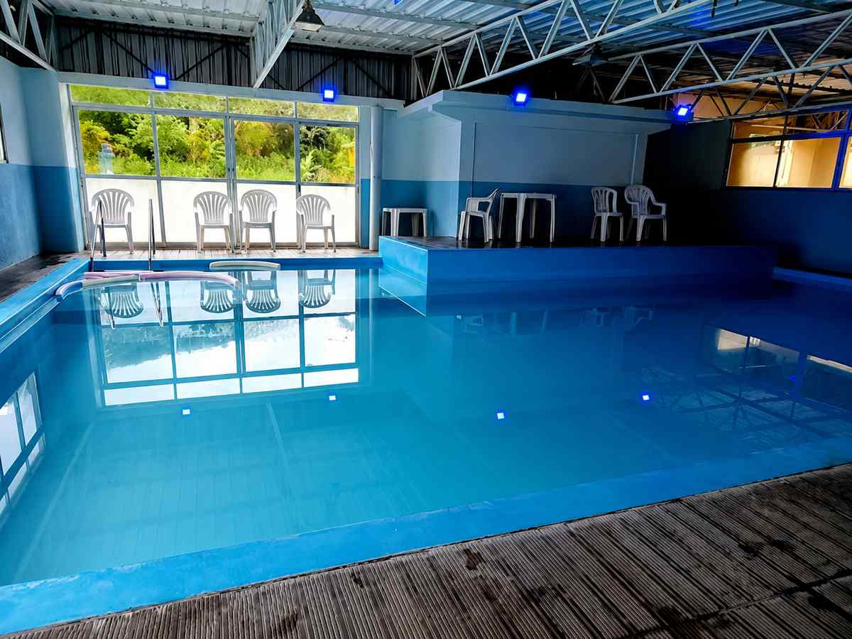 Heated pool with blue lighting and a poolside seating deck